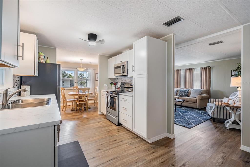 A kitchen with white cabinets and stainless steel appliances opens into a dining area and living room — 257 SAGO PALM STREET, LARGO, FL