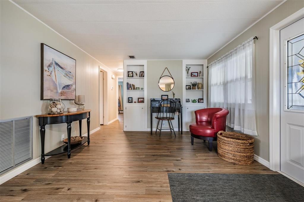 A living area features wood-look flooring, a red armchair, a desk, and built-in shelving — 257 SAGO PALM STREET, LARGO, FL