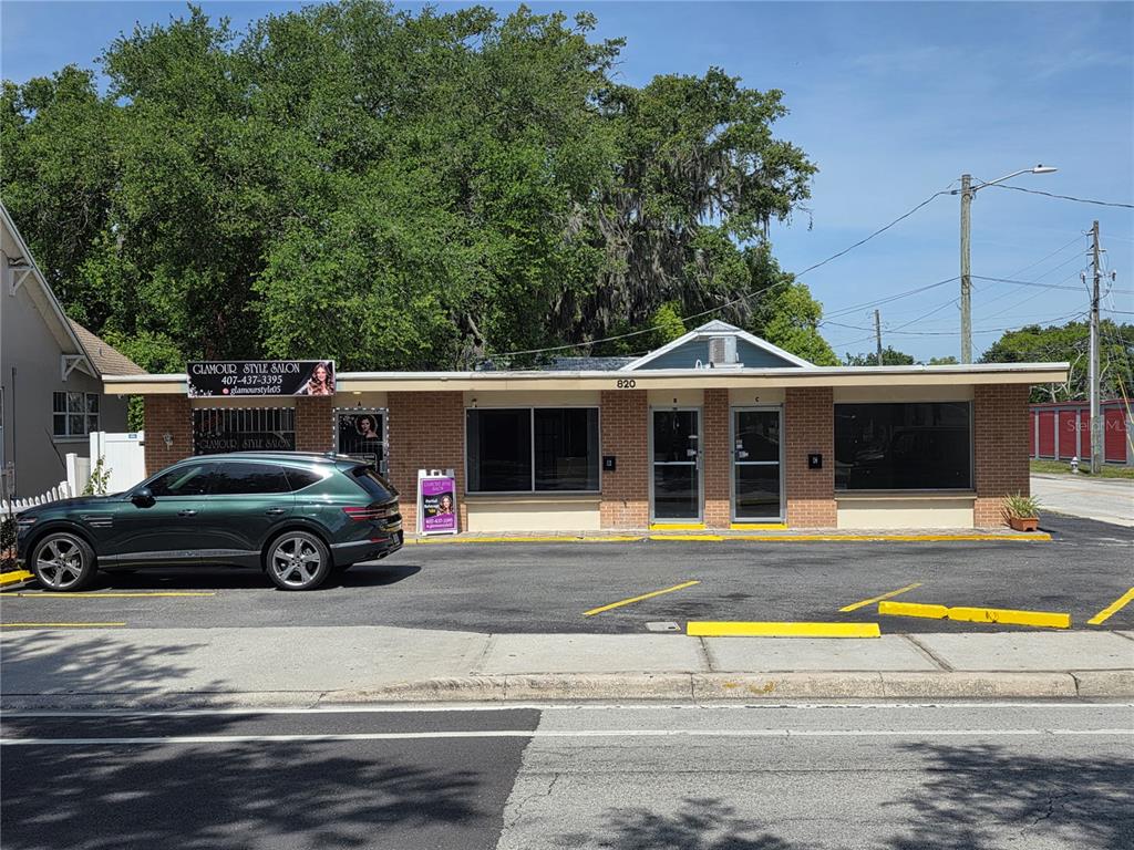 A single-story brick commercial building with two glass entry doors and a parked green SUV — 820 N MAIN STREET, KISSIMMEE, FL