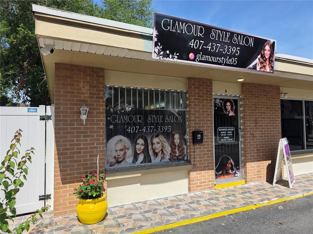 The exterior of a brick commercial building features a salon sign and glass door — 820 N MAIN STREET, KISSIMMEE, FL