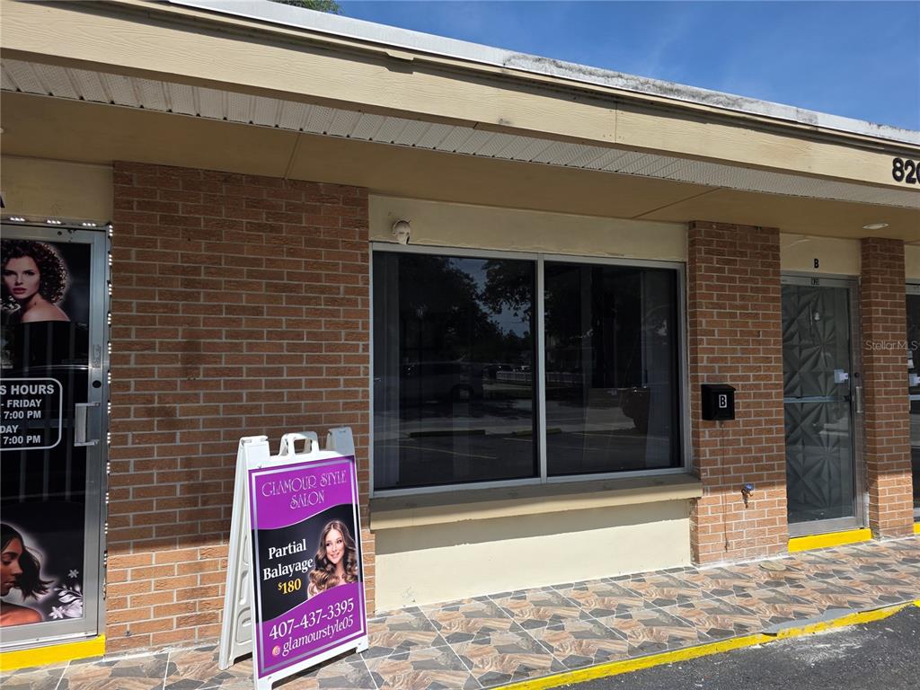 The exterior of a brick commercial building features a salon storefront with a sandwich board — 820 N MAIN STREET, KISSIMMEE, FL