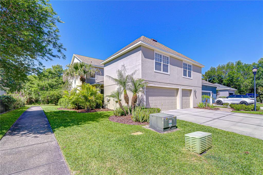 A two-story house with a beige stucco exterior, a two-car garage, and a landscaped lawn — 6135 CHURCHSIDE DRIVE, LITHIA, FL