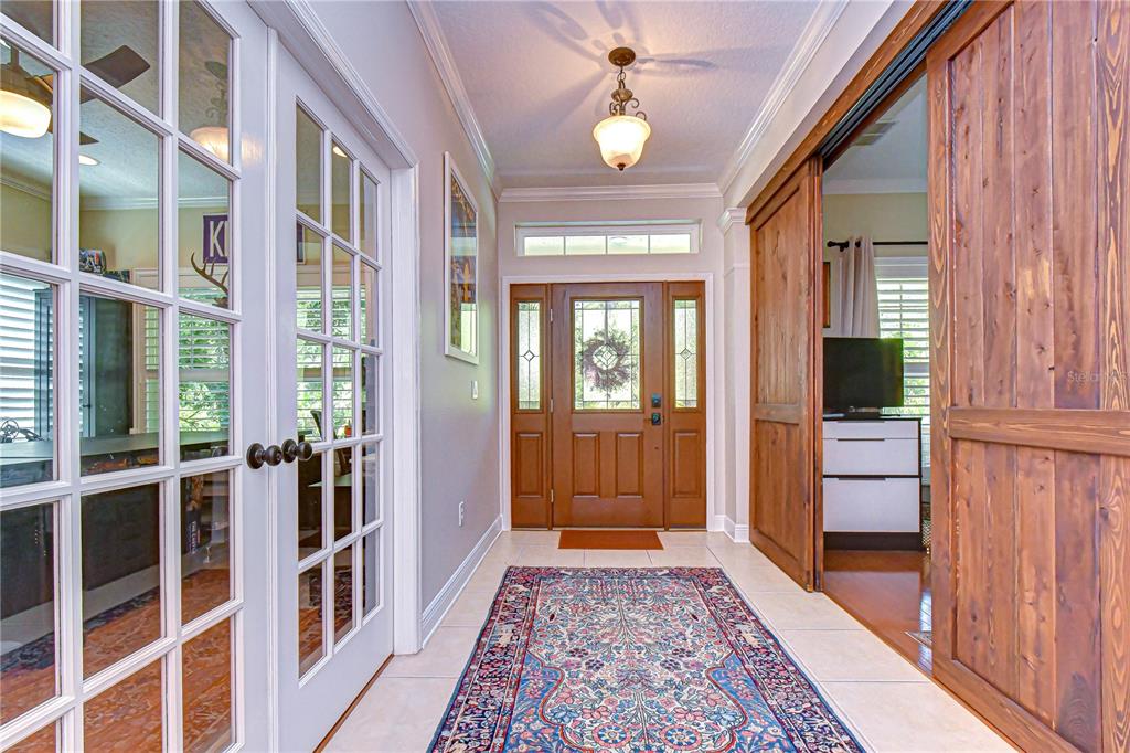 A tiled entryway features a patterned rug, a wooden front door, and sliding barn doors — 6135 CHURCHSIDE DRIVE, LITHIA, FL