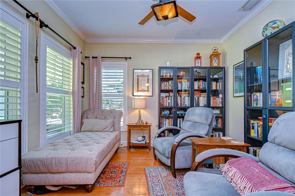 A cozy reading room features a chaise lounge, two armchairs, bookshelves, and hardwood flooring — 6135 CHURCHSIDE DRIVE, LITHIA, FL