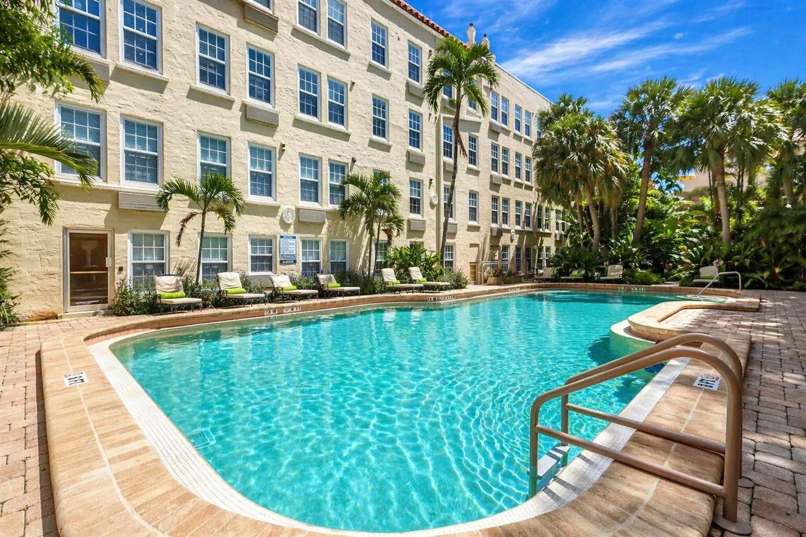 A swimming pool sits in a courtyard surrounded by a multi-story building and palm trees — 235 Sunrise # 3244, Palm Beach FL 33480, PALM BEACH, FL