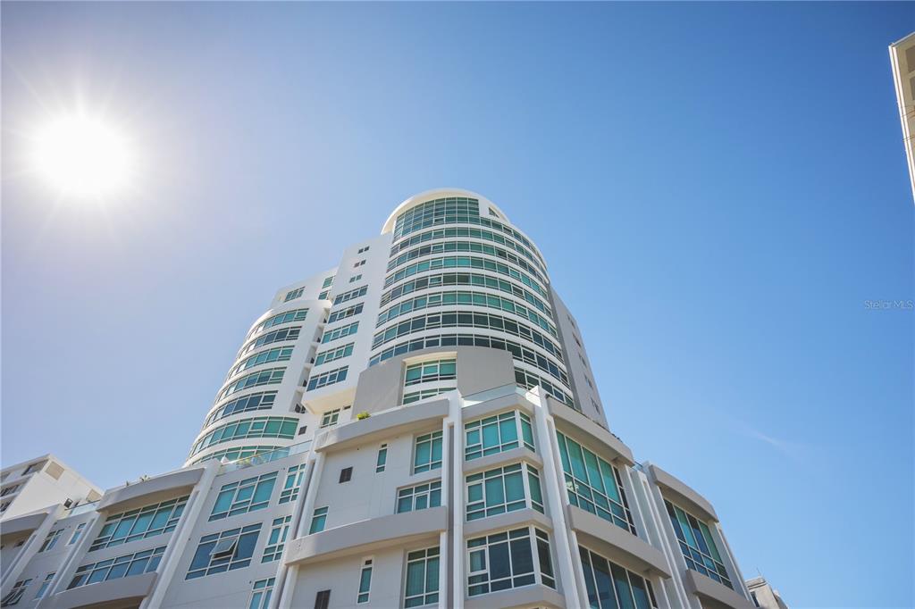 A low-angle exterior view of a modern high-rise building against a clear blue sky — 1052 ASHFORD AVE UNIT 9B, SAN JUAN, PR