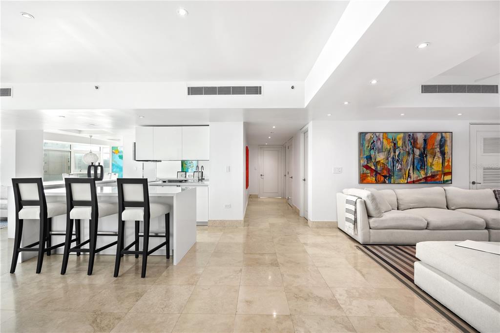 A modern open-concept living area features a white kitchen island, bar stools, and tiled floors — 1052 ASHFORD AVE UNIT 9B, SAN JUAN, PR