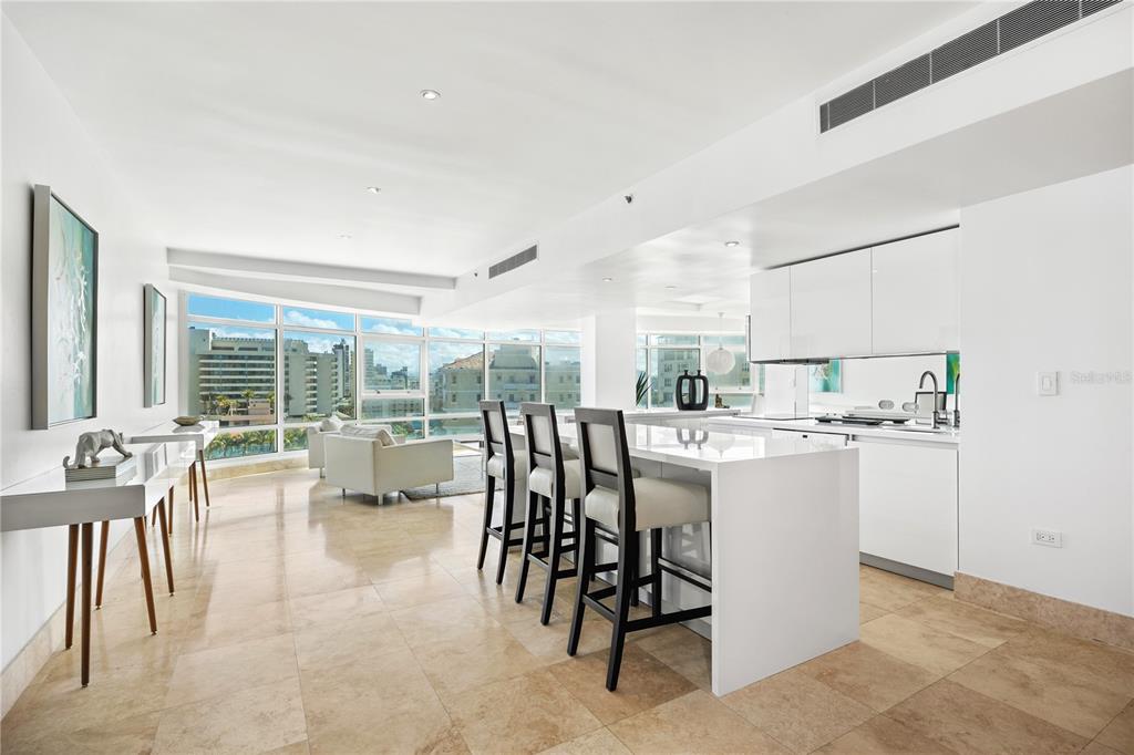 A modern kitchen and living area with white cabinetry, a breakfast bar, and tile flooring — 1052 ASHFORD AVE UNIT 9B, SAN JUAN, PR