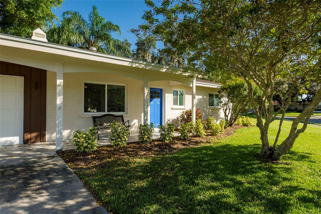 A single-story house with a white brick exterior, a blue front door, and a covered porch — 3005 CHASE CIRCLE, SARASOTA, FL