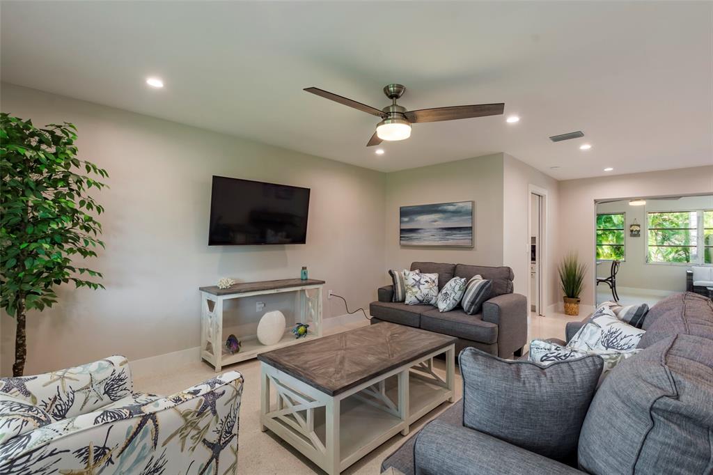 A living room features a gray sofa, patterned armchair, coffee table, and wall-mounted television — 3005 CHASE CIRCLE, SARASOTA, FL