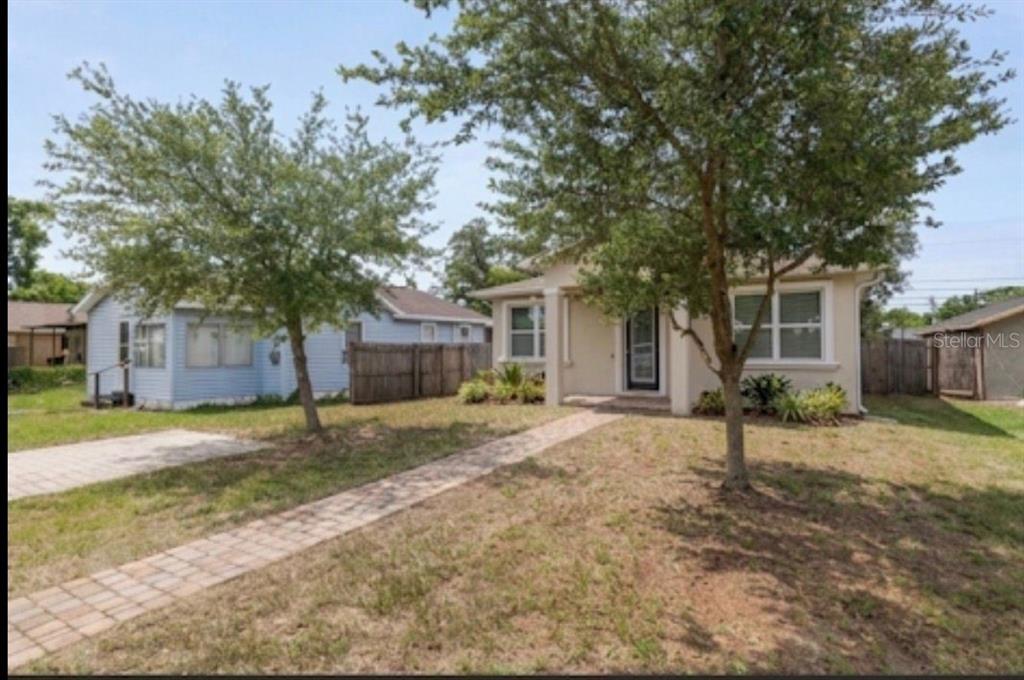 A light-colored house with a brick walkway and two trees in the front yard — 3725 57TH AVENUE N, ST PETERSBURG, FL