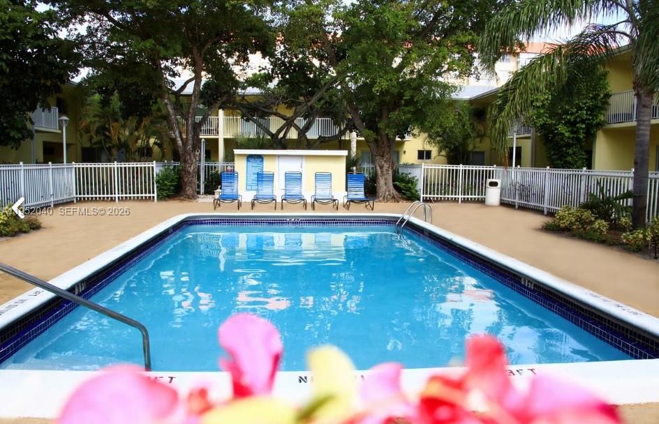 A rectangular swimming pool is surrounded by a white fence and lounge chairs — 4271 NW 5th St # 106, Plantation FL 33317, PLANTATION, FL
