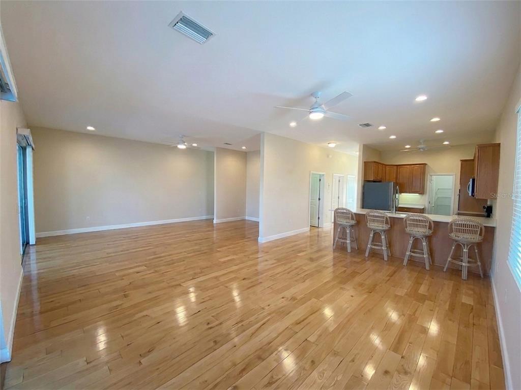 An open-concept living area features hardwood floors, a kitchen island with bar stools, and recessed lighting — 6249 LONNIE LEE LANE, HUDSON, FL