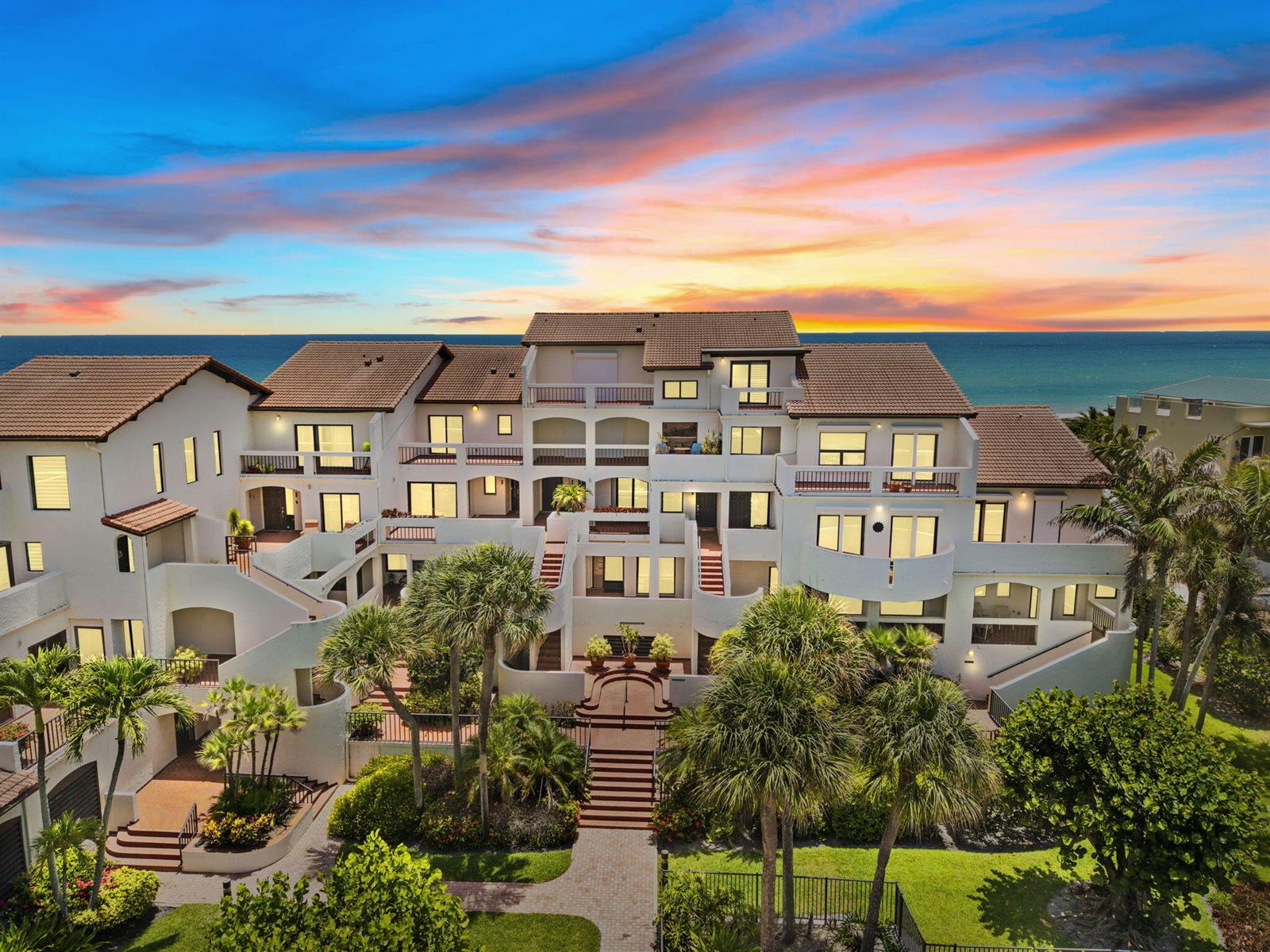 An aerial view of a multi-story beachfront condominium complex with palm trees and sunset sky — 4561 NE Ocean Drive # 29, Jensen Beach FL 34957, JENSEN BEACH, FL