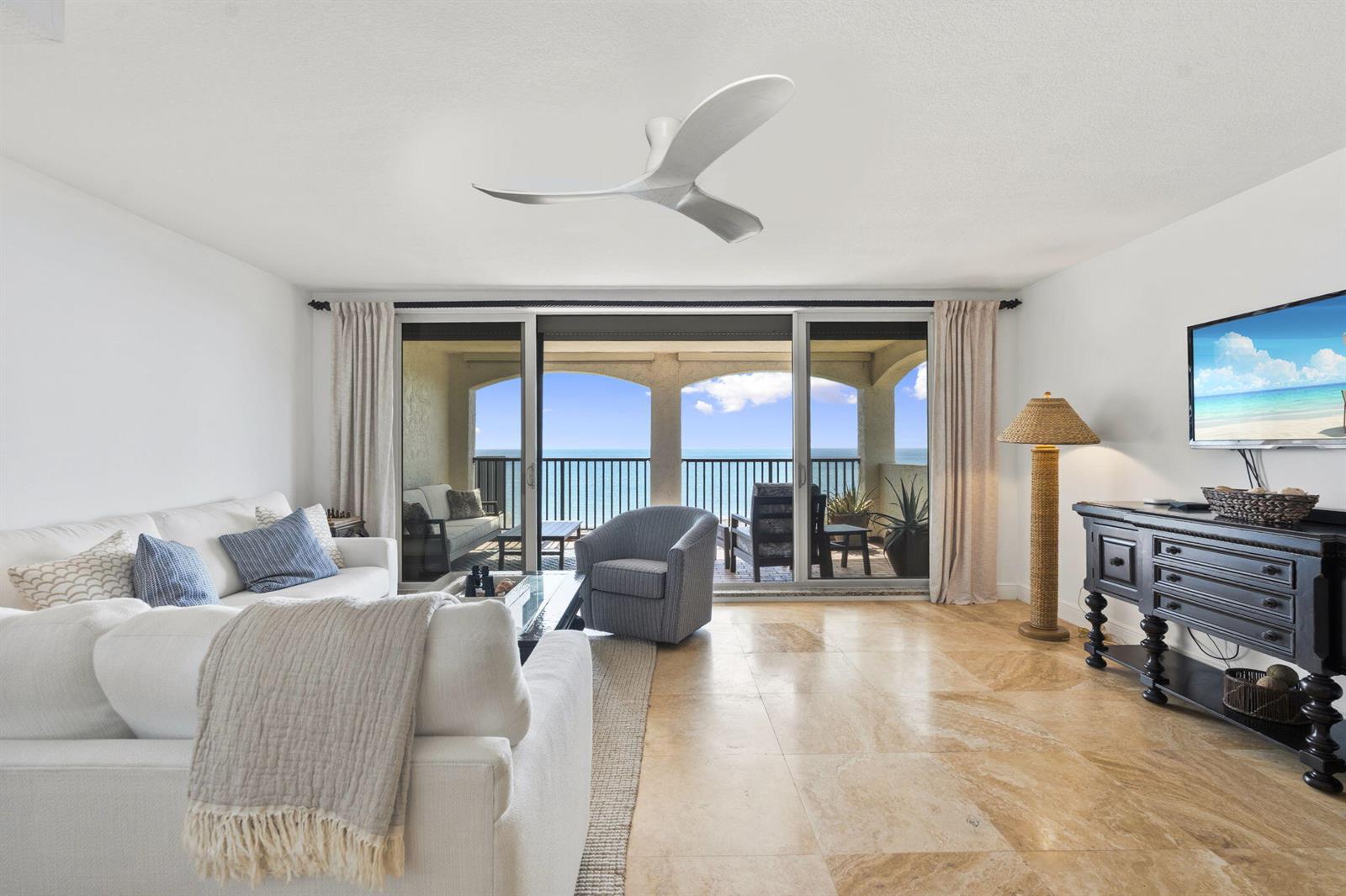 A living room features a white sofa, a blue armchair, and a balcony overlooking the ocean — 4561 NE Ocean Drive # 29, Jensen Beach FL 34957, JENSEN BEACH, FL