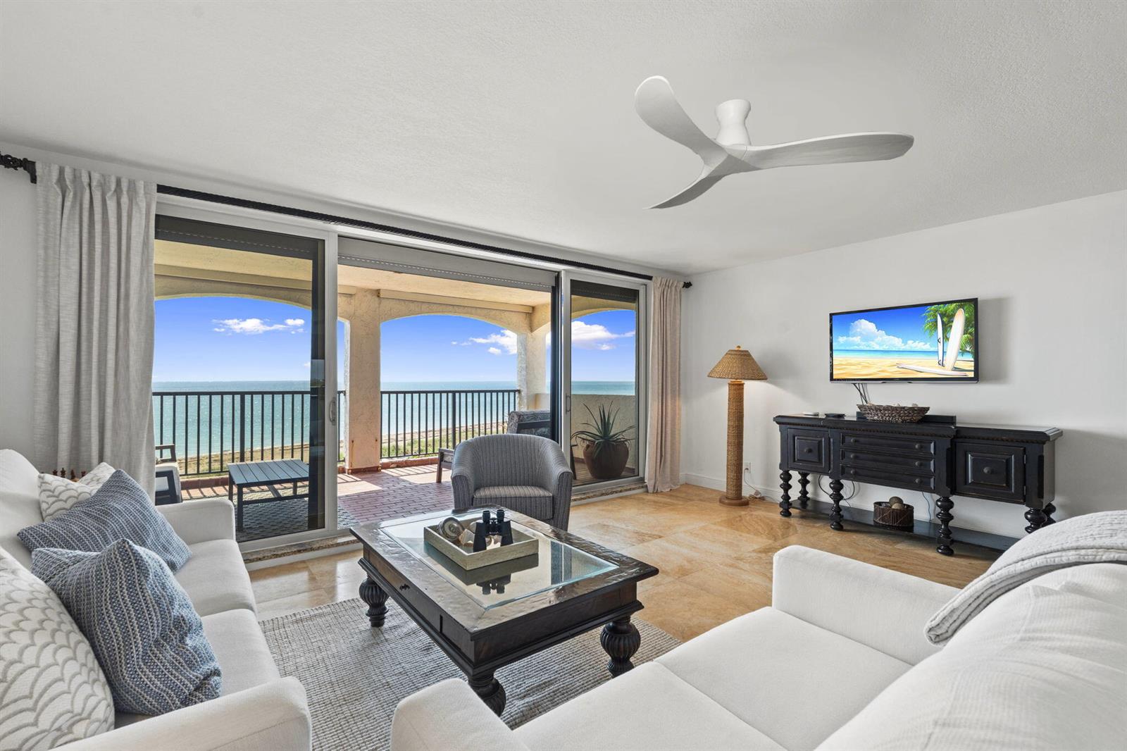 A living room with white sofas, a dark wood coffee table, and a balcony view — 4561 NE Ocean Drive # 29, Jensen Beach FL 34957, JENSEN BEACH, FL