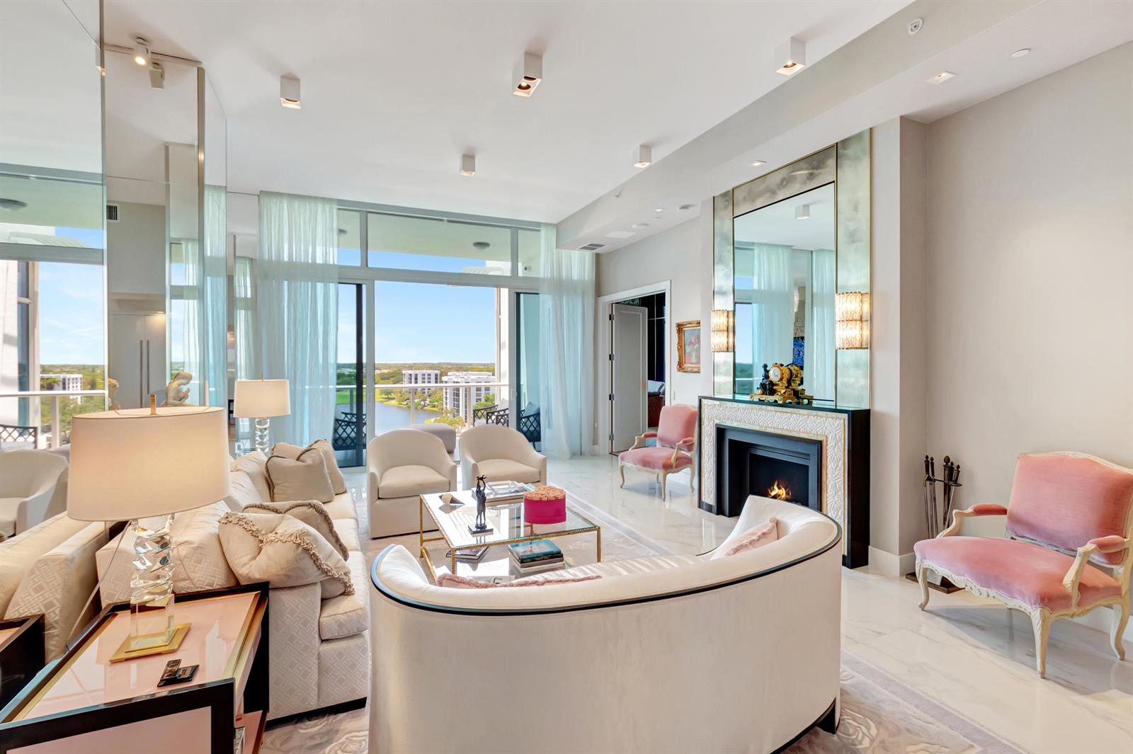 A bright living room features a fireplace, plush seating, marble floors, and a balcony view — 20155 Boca West Drive # c902, Boca Raton FL 33434, BOCA RATON, FL