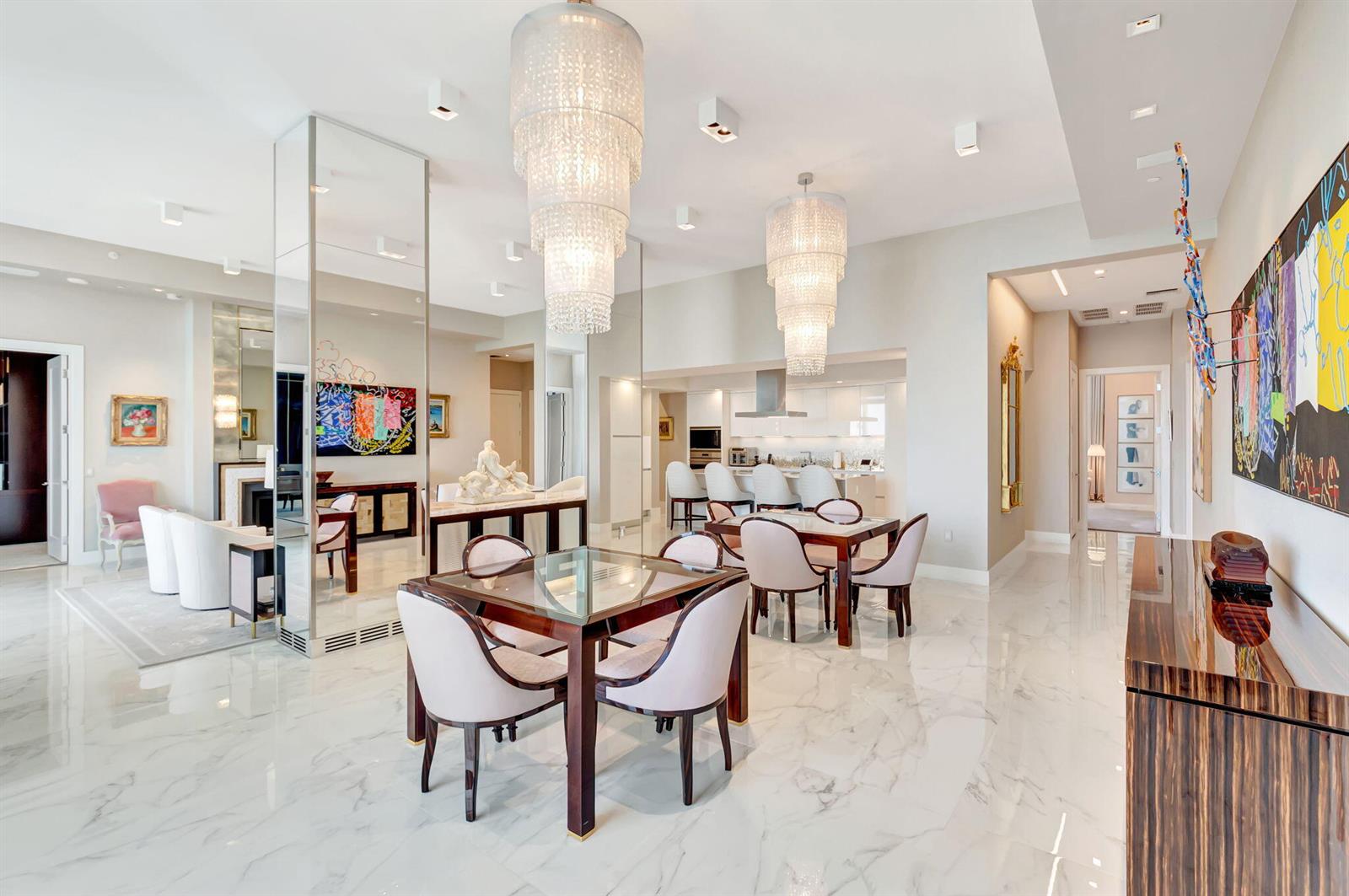 A dining area with two glass-topped tables, crystal chandeliers, and white marble floors — 20155 Boca West Drive # c902, Boca Raton FL 33434, BOCA RATON, FL