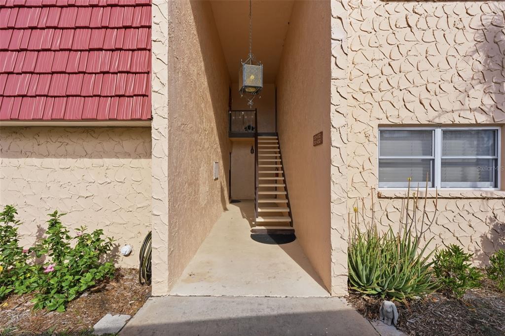 An exterior view of a building entrance featuring a staircase leading to an upper level — 212 CEDARWOOD CIRCLE UNIT 212, SEMINOLE, FL
