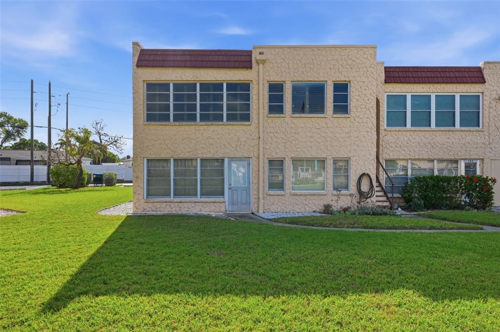 A two-story stucco townhouse with a flat roof and multiple windows faces a grassy lawn — 212 CEDARWOOD CIRCLE UNIT 212, SEMINOLE, FL