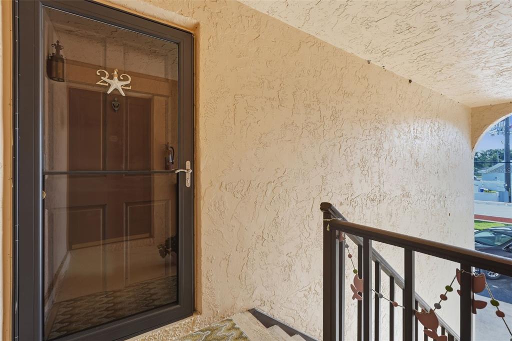 A storm door with the number 212 leads to an apartment entrance with textured walls — 212 CEDARWOOD CIRCLE UNIT 212, SEMINOLE, FL