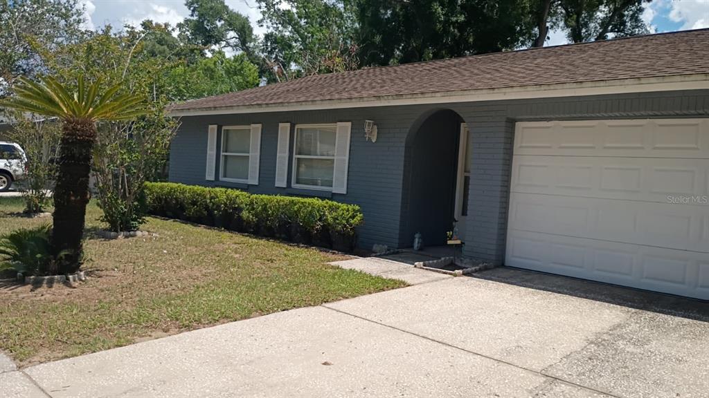 A gray brick house features a white garage door, white shutters, and a front lawn — 721 REGENT CIRCLE S, BRANDON, FL