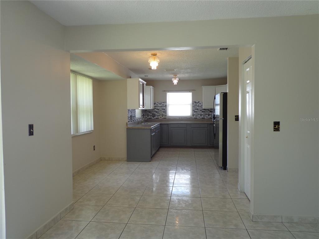 A kitchen with gray lower cabinets, white upper cabinets, tiled backsplash, and light-colored floor tiles — 721 REGENT CIRCLE S, BRANDON, FL