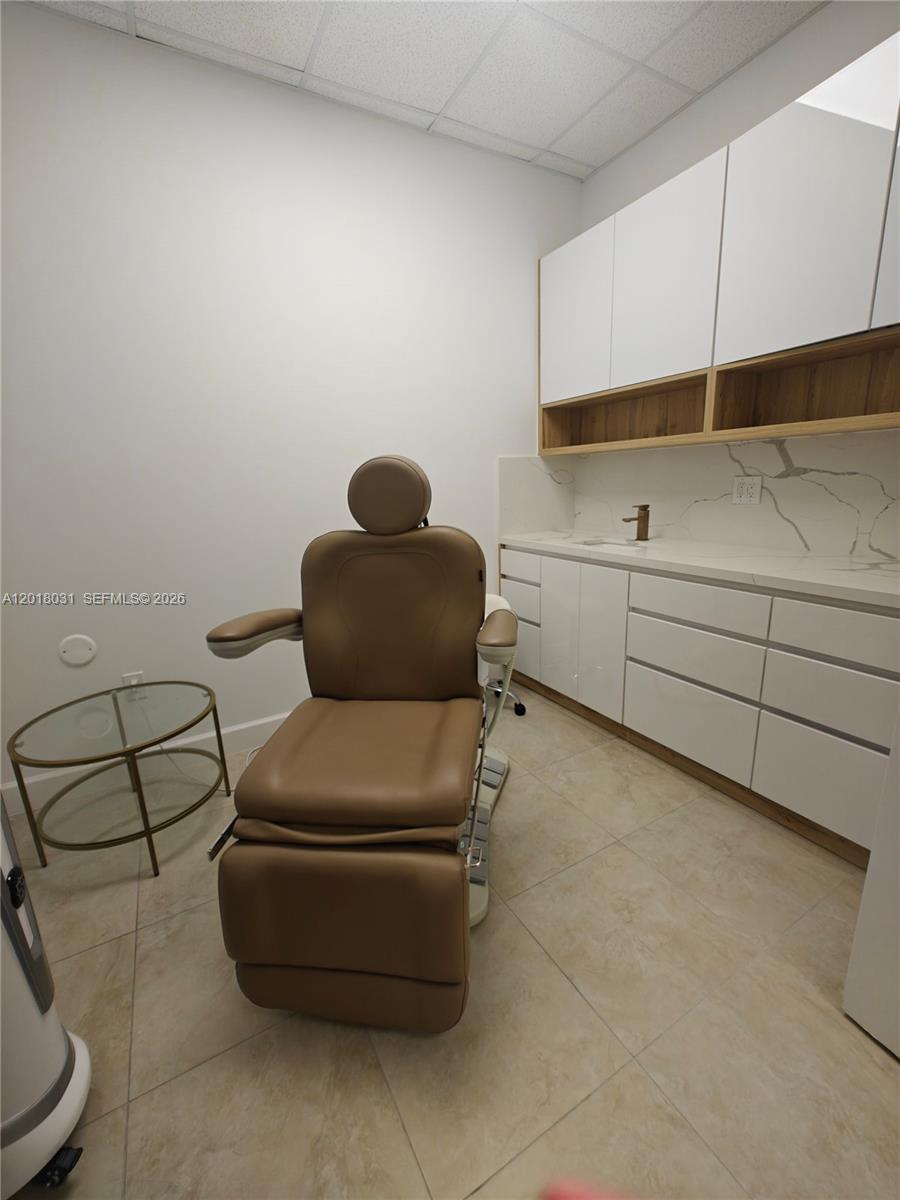 A medical exam room features a tan treatment chair, white cabinetry, and a marble countertop — 175 SW 7th St # 2006, Miami FL 33130, MIAMI, FL