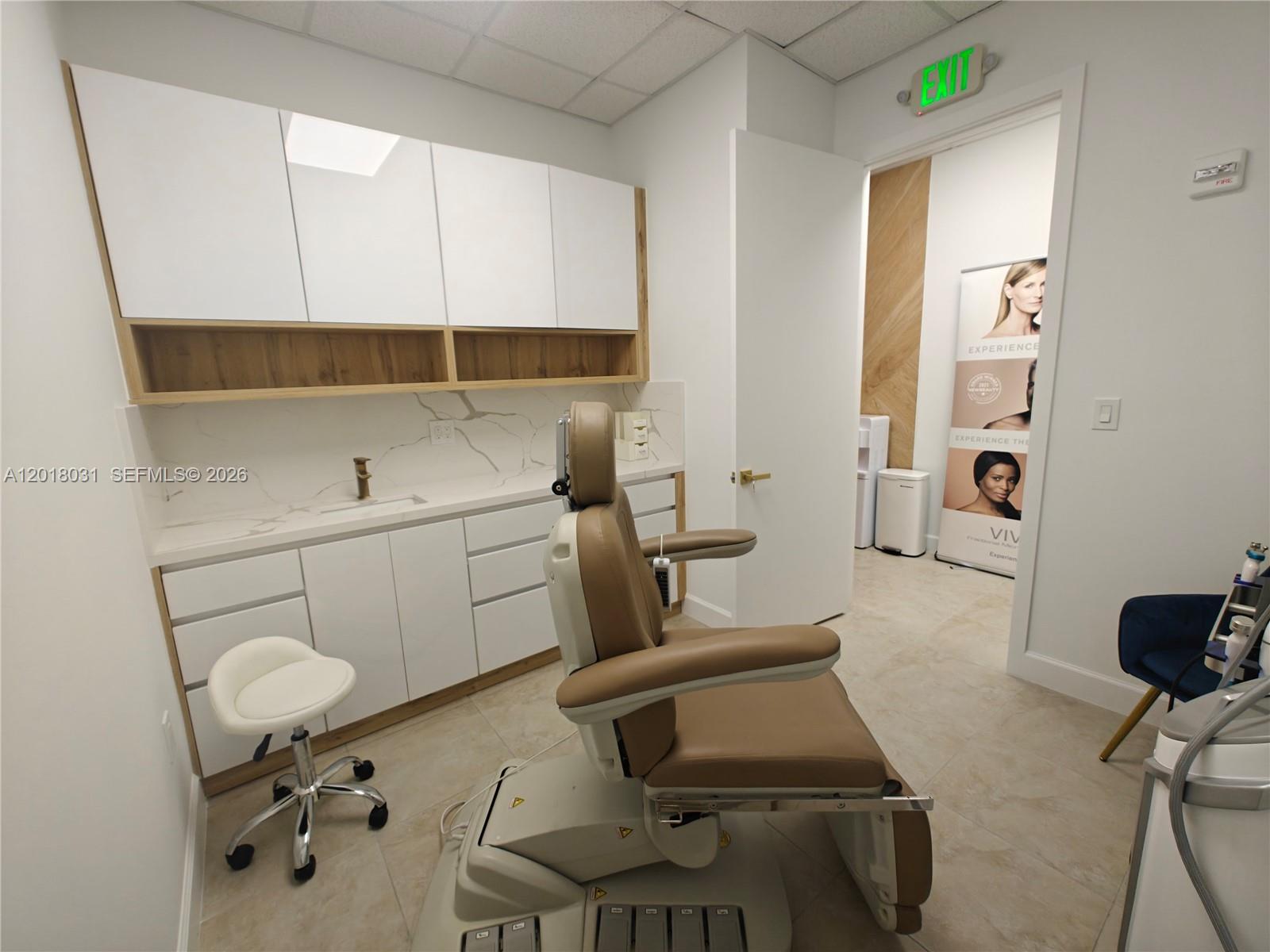 A medical treatment room features a procedure chair, white cabinetry, a sink, and tile flooring — 175 SW 7th St # 2006, Miami FL 33130, MIAMI, FL