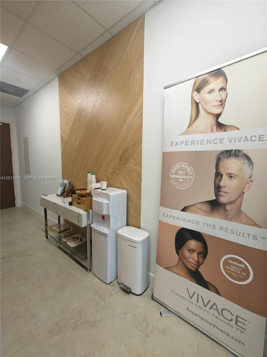 A waiting area features a wood-paneled wall, a marble console table, and a promotional banner — 175 SW 7th St # 2006, Miami FL 33130, MIAMI, FL