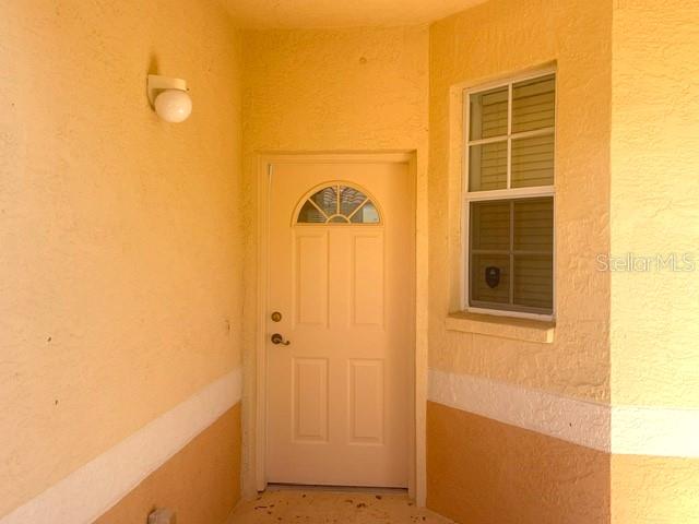 A tan two-story building exterior features a staircase, a balcony, and a large window — 4270 VICENZA DRIVE UNIT B40, VENICE, FL