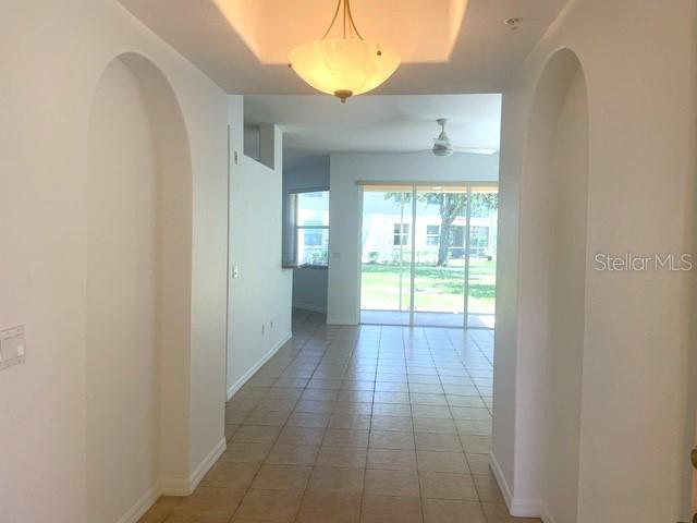 A tiled hallway with arched entryways leads to a living area with sliding glass doors — 4270 VICENZA DRIVE UNIT B40, VENICE, FL