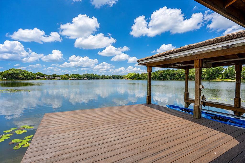 A wooden boat dock with a covered slip extends over a calm lake under blue skies — 2914 REEF KNOT PLACE, WINTER PARK, FL
