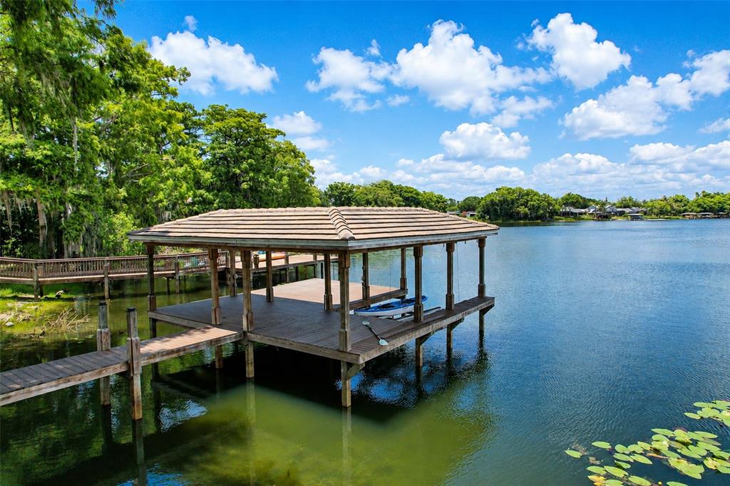 A wooden boat dock with a covered roof sits on a calm lake — 2914 REEF KNOT PLACE, WINTER PARK, FL