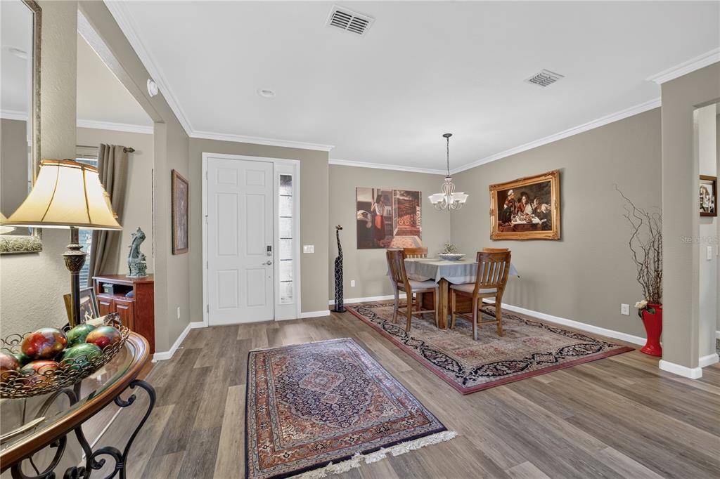 A dining area with a table, chairs, area rugs, and a front door entrance — 9824 SW 72ND LANE, OCALA, FL