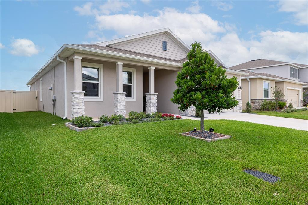 A single-story house with a beige stucco exterior, stone-accented porch columns, and a front lawn — 3413 IVY HOLLOW DRIVE, PLANT CITY, FL