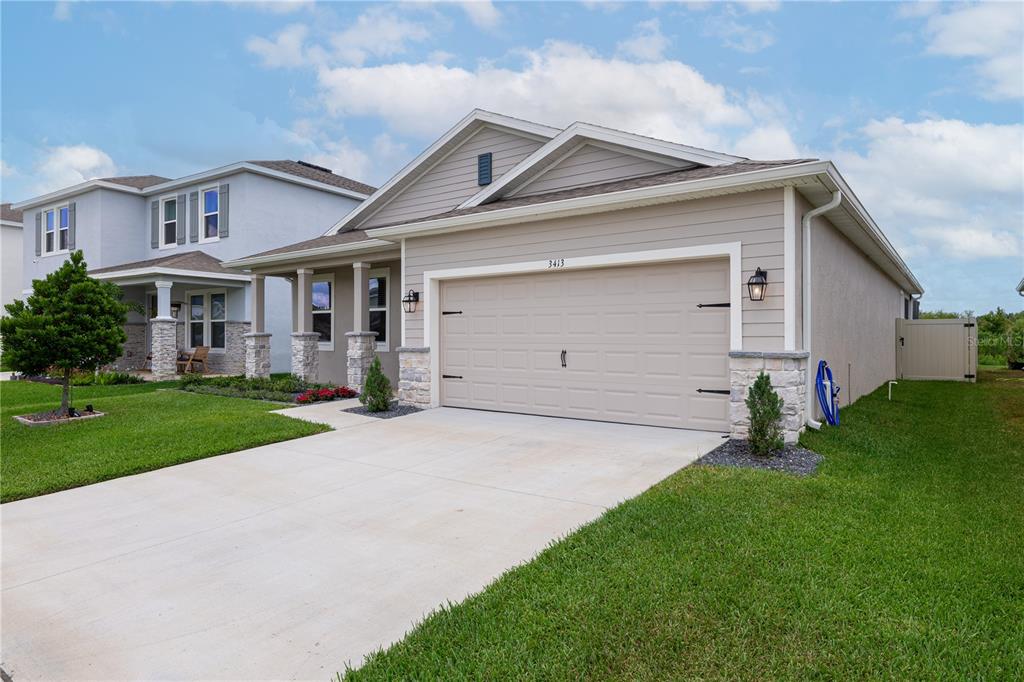 A tan single-story house with a two-car garage, stone accents, and a concrete driveway — 3413 IVY HOLLOW DRIVE, PLANT CITY, FL