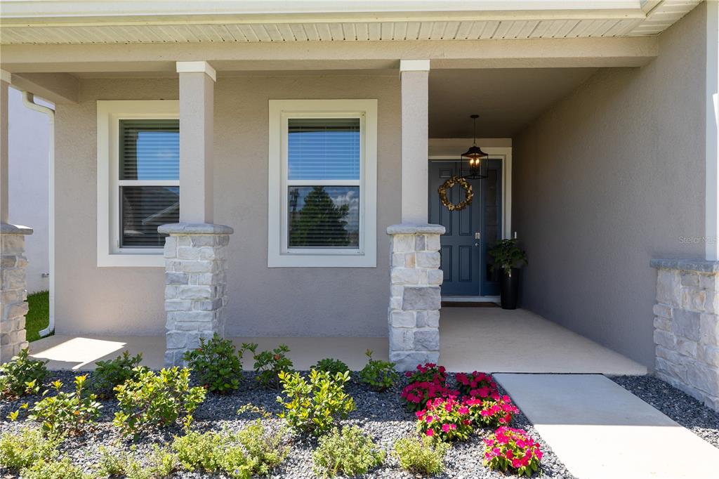 A front porch with stone-based columns, a blue door, and a landscaped garden bed — 3413 IVY HOLLOW DRIVE, PLANT CITY, FL