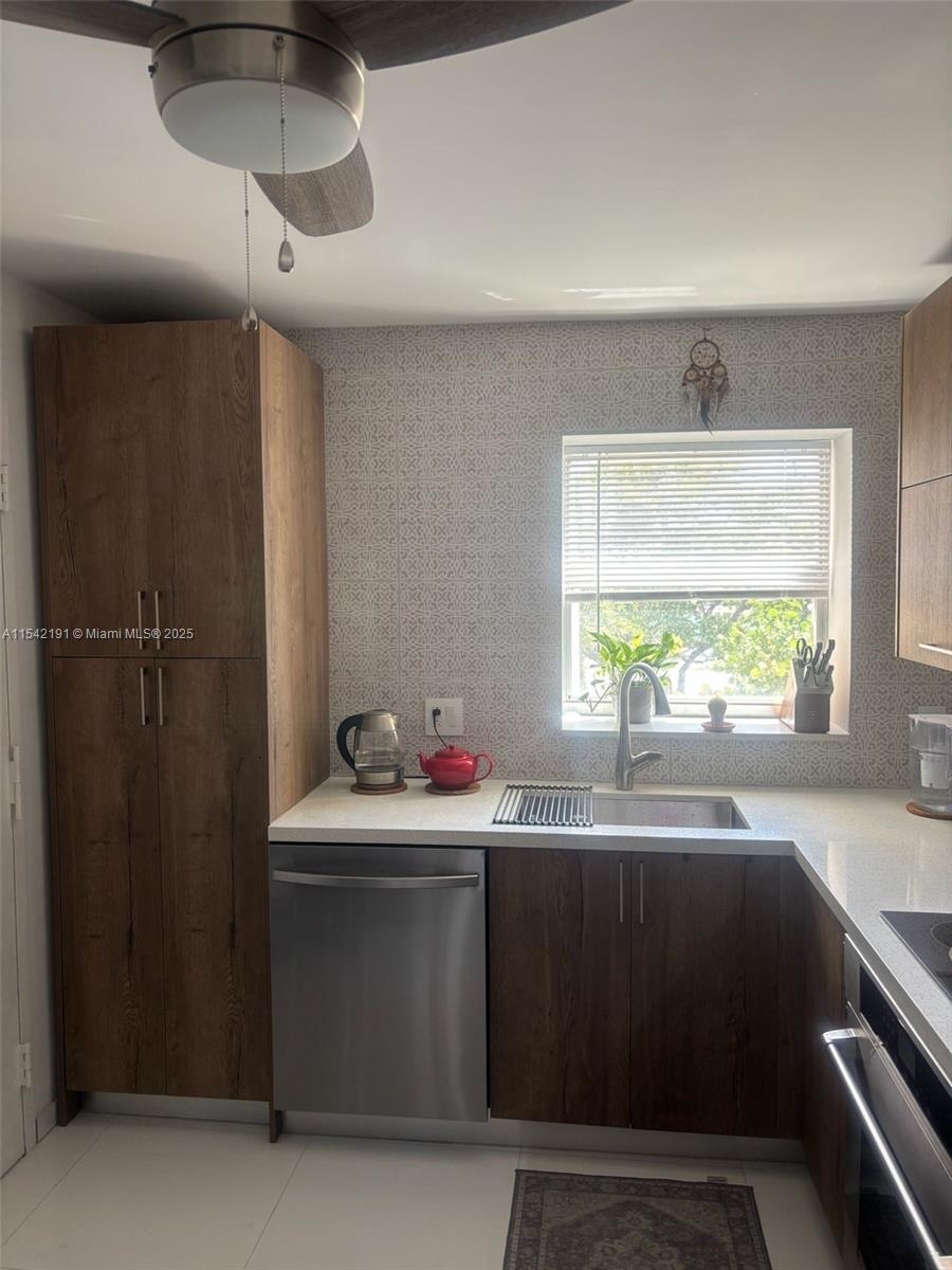 A kitchen features wood-grain cabinets, stainless steel appliances, a white countertop, and a patterned backsplash — 1865 S Ocean Dr # 4F, Hallandale Beach FL 33009, HALLANDALE BEACH, FL