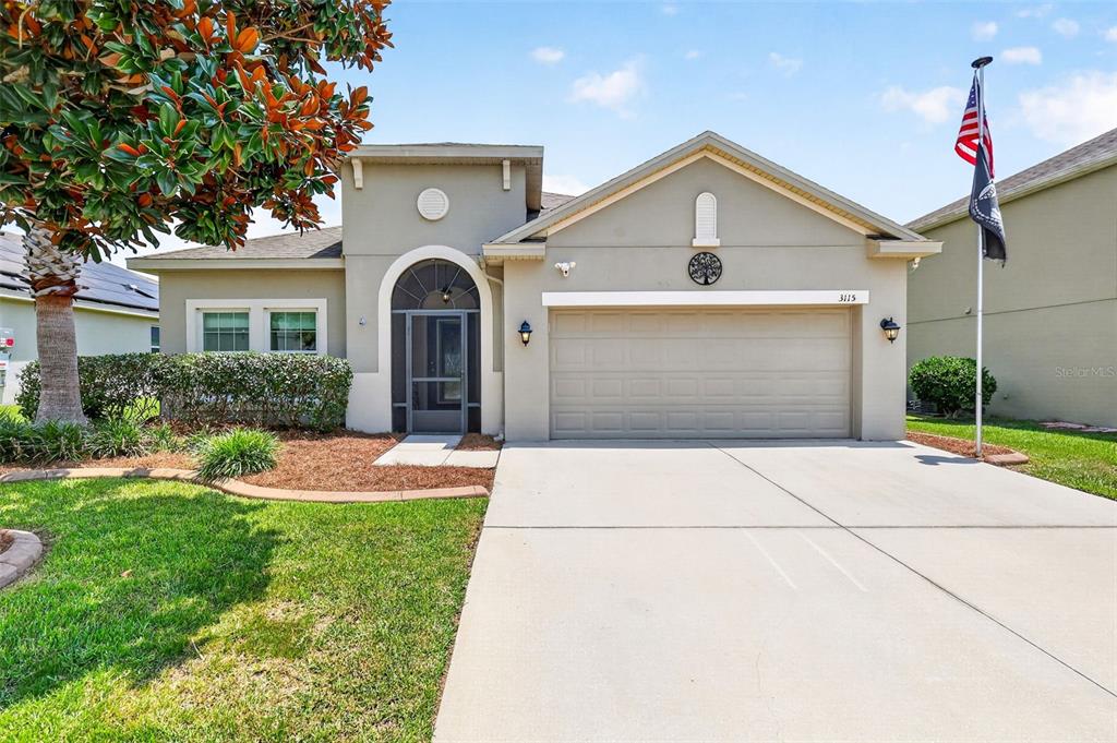 A single-story house with a beige stucco exterior, a two-car garage, and a front entryway — 3115 ZANDER DRIVE, GRAND ISLAND, FL