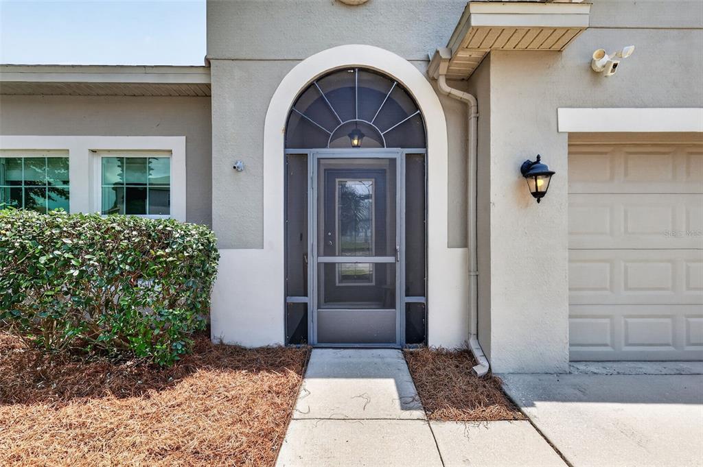 A front entrance features a screen door, arched transom window, and an adjacent garage door — 3115 ZANDER DRIVE, GRAND ISLAND, FL