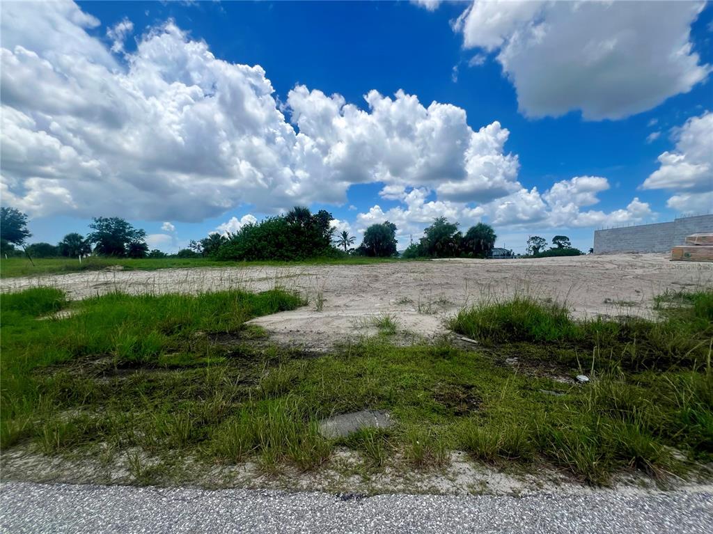 A vacant, sandy residential lot is shown under a bright, cloudy blue sky — 530 NW 18TH PLACE, CAPE CORAL, FL