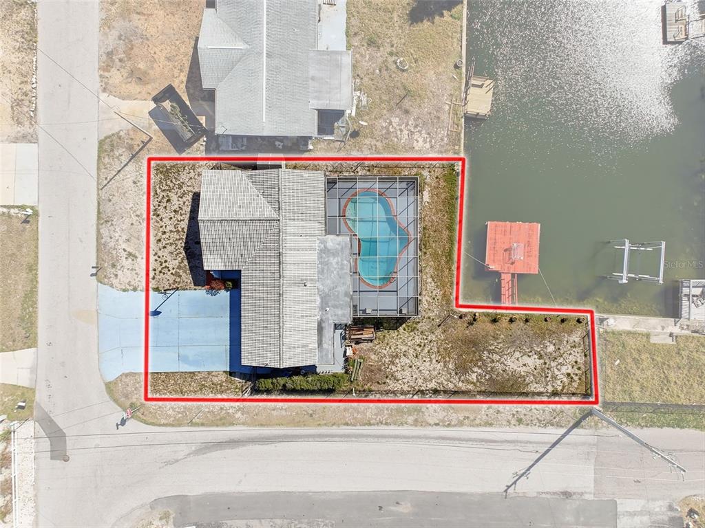 An aerial view shows a house with a screened pool and dock on a waterfront lot — 13701 VERONICA DRIVE, HUDSON, FL