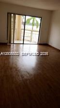An empty room with wood-look flooring features a large sliding glass door leading to a balcony — 8290 LAKE DR # 412, Doral FL 33166, DORAL, FL