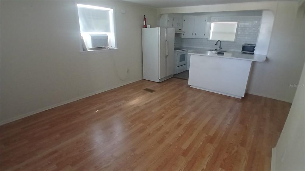 A kitchen with white cabinets and appliances opens into a living area with wood flooring — 542 DIVISION STREET, TARPON SPRINGS, FL