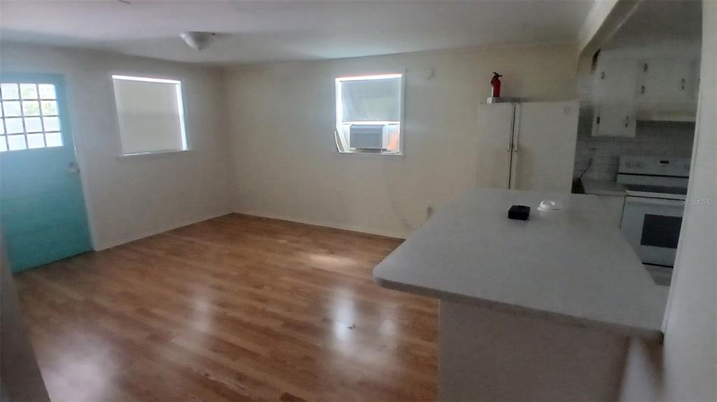 A kitchen and living area feature light wood flooring, white walls, and a breakfast bar — 542 DIVISION STREET, TARPON SPRINGS, FL