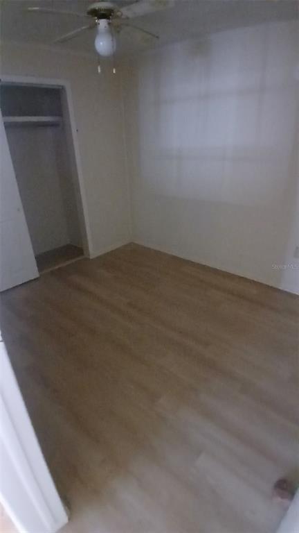 An empty bedroom with light wood-look flooring, a ceiling fan, and an open closet door — 542 DIVISION STREET, TARPON SPRINGS, FL