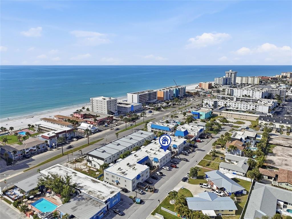 An aerial view shows a multi-story apartment complex near a beach and ocean — 17035 GULF BOULEVARD UNIT 216, ST PETERSBURG, FL