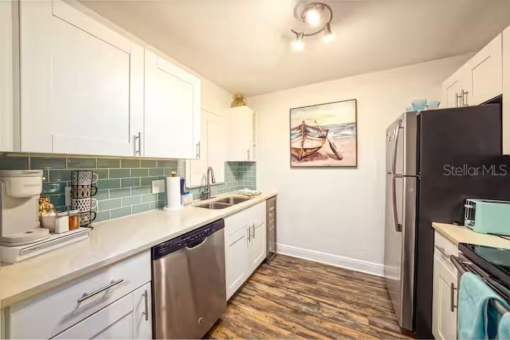 A kitchen features white cabinetry, a teal subway tile backsplash, and stainless steel appliances — 17035 GULF BOULEVARD UNIT 216, ST PETERSBURG, FL