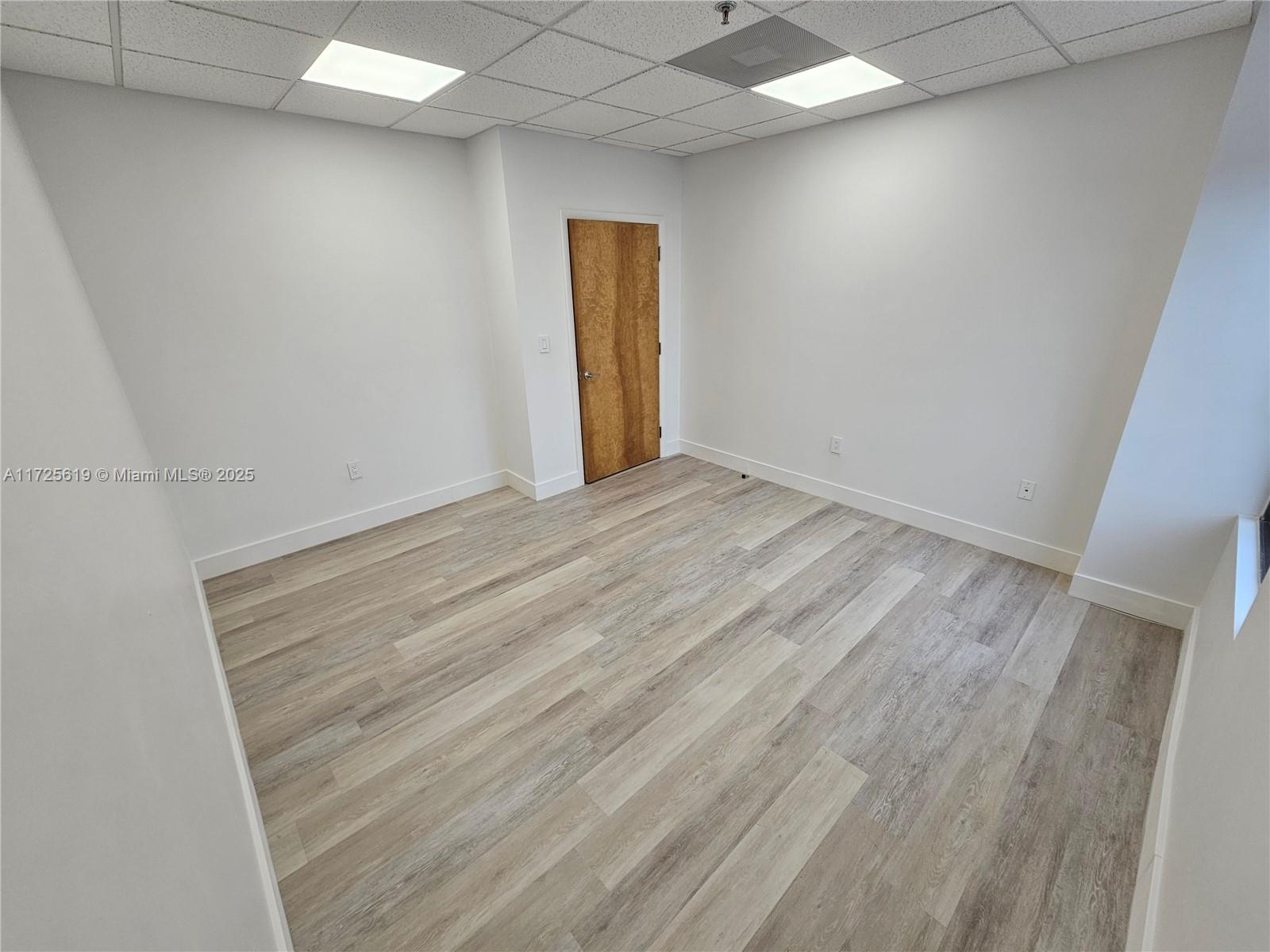 An empty office room features white walls, light wood-look flooring, and a drop ceiling — 12550 Biscayne Blvd # 4, North Miami FL 33181, NORTH MIAMI, FL